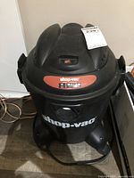 Front and top view of black Shop-Vac wet/dry vacuum showing handle, power switch and capacity badge
