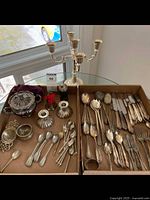Photo showing entire lot arranged on a table including candle holder and multiple trays of flatware and table accessories