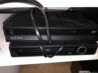 Photo showing Apex digital TV converter on top and Sylvania DVD player below with power cord wrapped around.