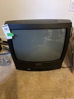 Front and top view of the black Sylvania CRT TV with a curved screen and visible scratches.