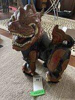 Left front angle of a carved wooden Asian mythical creature figurine showing facial details and body painting