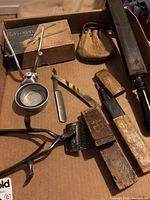 Overview of all items in the set including hair clipper, straight razor, strop, and leather pouch arranged in cardboard box.
