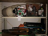 Photo of yard sprayer, garden wire reel, gnome statue, deer repellent spray bottle, and gardening clippers on metal shelves.