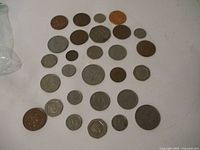 Image showing a spread of 27 British coins of mixed metals and sizes on a white surface.