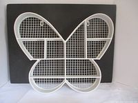 Front view of white metal butterfly shaped shelf showing overall shape and compartments.