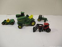 Five model tractors on plain white surface