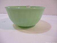 Side view of opaque green jadeite glass mixing bowl with flared rim and smooth finish.