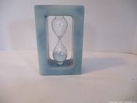 Front view of the alabaster hourglass showing the rectangular frame and clear glass with white sand inside.