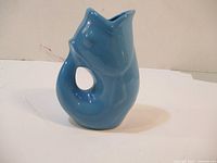 Side view of a blue ceramic gurgle jug showing loop handle and spout
