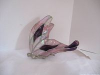 Side view showing stained glass wings in pink and purple hues with silver metal frame and angel base.