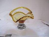 Front view of amber glass basket centerpiece with silver-tone base showing the scalloped rim and handle.