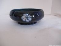 Side view of the dark blue ceramic dish showing the floral pattern and shape.