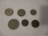 Six old British coins displayed on a white surface showing front faces. Coins vary in size and color.