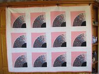 Full view of the quilt showing the layout of twelve blocks with fan patterns on pink and white background.