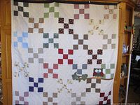 Full view of quilt showing patchwork pattern in multiple colors and owl applique on branch.