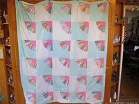 Full view of the patchwork quilt hung on a wooden shelf background showing pattern and size