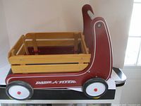 Side view of the red Radio Flyer kids wagon buggy with wooden slat sides and white wheels.