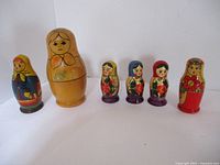 Six dolls lined up show individual nesting doll components from largest to smallest.