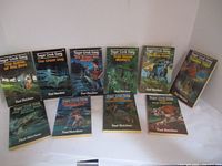 Ten paperback books titled Sugar Creek Gang laid out in two rows on a white surface against a white wall. Bright and colorful illustrated covers show different adventure scenes, each with the author name Paul Hutchens.