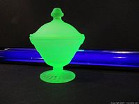 Green uranium glass dish with lid, glowing under UV light showing bright green fluorescence