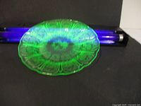 Plate under UV light showing bright green fluorescence of uranium glass, top angle display