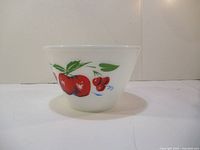 Side view of Fire King bowl with red apple and cherry design on white milk glass, showing shape and decoration