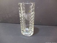 Front angled view of clear glass vase showing textured bubble pattern on one side and smooth flat rim.