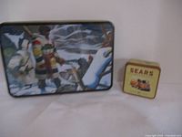 Both vintage tins displayed on a white surface showing details and size comparison.
