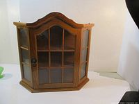 Frontal view of wood showcase cabinet with glass window panes and arched top design