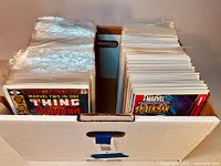 Long view of cardboard box filled with bagged comics, front row shows Marvel Two-In-One Thundra and Marvel Spider-Man #1
