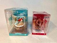 Photo of both unopened Disney D-Stage figurines, Ariel and Anna, showing packaging and clear bonded boxes in shrink wrap.