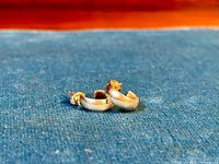 Pair of 92.5 sterling silver 3/4 hoop earrings with butterfly backings, shown on blue fabric background.