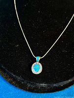 Front view of pendant and necklace on black background showcasing the vibrant blue fire opal in the pendant and the delicate silver chain.