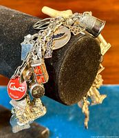 Bracelet on black display showing curb-link chain and multiple hanging charms from one side