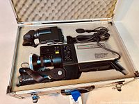 Image showing the Hitachi Color Video Camera C850 inside the foam-lined carrying case along with attached microphone and eyepiece accessory.
