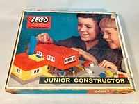 Front view of original LEGO System by Samsonite 717 Junior Constructor box with image of children playing and a constructed house model.