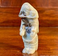 Front view of small soapstone Inuit carving figurine by Youtie Soudloo, showing detailed face and clothing.