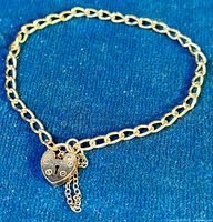 Bracelet laid flat on blue background showing full curb link chain and heart clasp