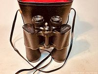 Vintage wide-angle binoculars showing the front lenses, focusing knob, and textured black barrel.