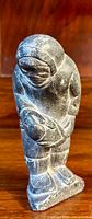 Front view of soapstone Inuit figure showing detailed carving holding object.