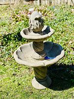 Front view of the two-tier grey resin pineapple fountain on grass.
