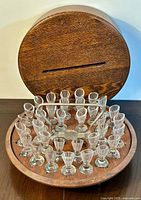 Photo showing entire communion cup set with mahogany carrier open, 31 clear glass cups visible arranged around metal handle.