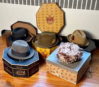 Overview of all five hats displayed on the floor with their original boxes, showing different styles and colors with the floral cap in front.