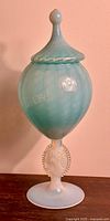 Full view of the antique opaline glass lidded goblet showing pale blue-green swirled body and pointed lid finial.