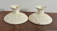 Pair of Wedgwood 'Patrician' pattern candlesticks shown side by side on wooden surface.