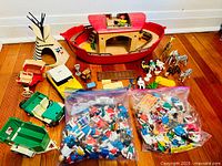 Overview of the toys spread on a wooden floor including the wooden Noah's Ark, animals, teepee, toy cars, and bags of figures