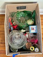 View into the box showing mixed glassware, ceramic items, and collectible tin inside