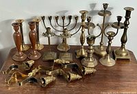 Overview of all pieces on wooden surface: wood and brass candlesticks, menorah, stocking hooks