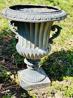 Full side view of the black classical garden urn with ornate handles and decorative fluted body on pedestal base.