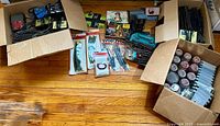 Wide view of multiple boxes containing HO scale train tracks, model buildings, ground materials, and train accessories.
